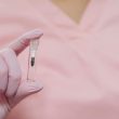A close-up view of a gloved hand holding a small medical sample vial, focusing on healthcare and medicine.