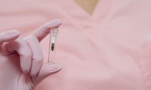 A close-up view of a gloved hand holding a small medical sample vial, focusing on healthcare and medicine.