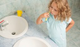 Child brushing teeth by sink, highlighting personal hygiene habits.
